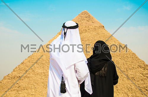 an Emiratie man and his wife looking at the giza pyramids