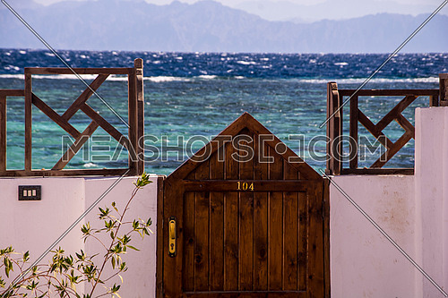A wooden door leading to the seashore  with the number 104 written on it