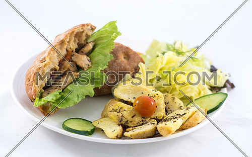A plate with a sandwich, salad and potatoes