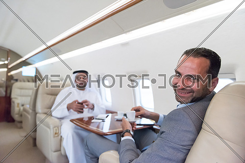 Young middle eastern successful businessman enjoyed by talking with Arab business partner while sitting in private jet