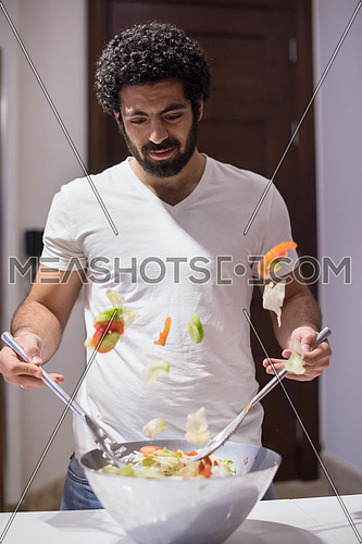 young middle east  man preparing salad in the kitchen with satisfaction