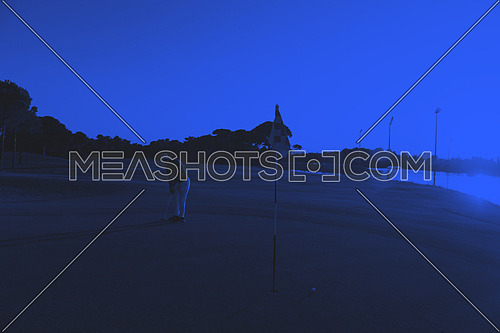 golf player hitting ball  with driver on course at beautiful sunset duo tone