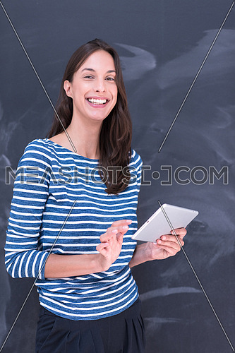 Happy young woman using tablet computer in front of chalk drawing board