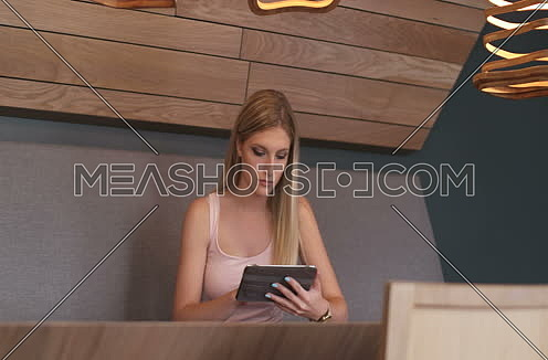 Pan right for blond woman sitting on table using tab
