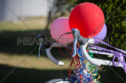 A bicycle decorated with ribbons and balloons in a garden
