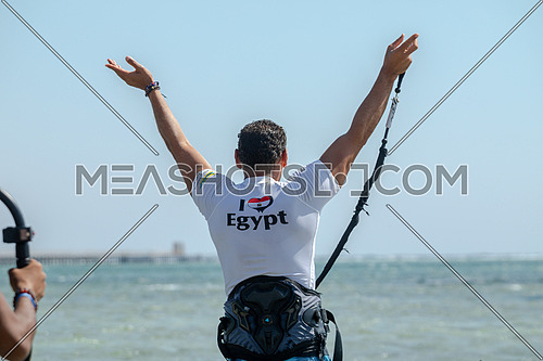 Male Kite surfing instructor wearing a white shirt wiritten on ( I Love Egypt) and  Egyptian flag heart shaped giving instruction to surfers  in the Red Sea by day.