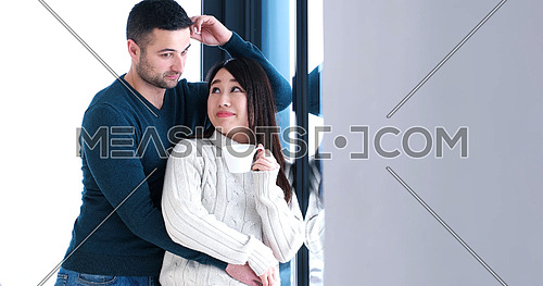 young multiethnic romantic couple enjoying morning coffee by the window in their luxury home