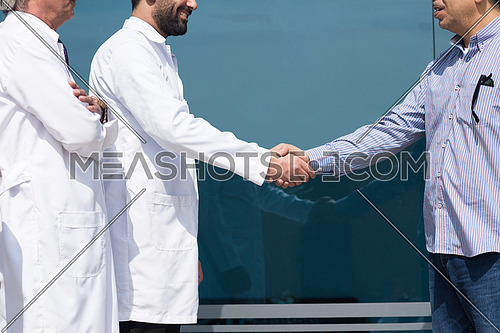 Smiling middle eastern doctor at the clinic giving an handshake to his patient, healthcare and professionalism concept