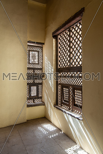 Corner of two Interleaved grunge wooden ornate windows - Mashrabiya - in stone wall at abandoned building