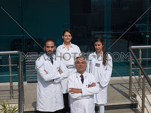 smiling team of doctors in front of modern hospital