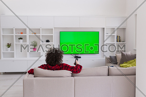 young handsome man in bathrobe enjoying free time watching television in his luxury home