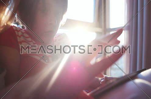 Mother And Daughter Using A Tablet  at home with sun rays coming from window