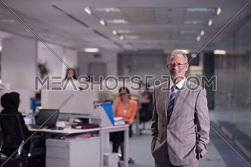 portrait of senior businessman as leader  at modern office interior  young  people group in background on their workplace