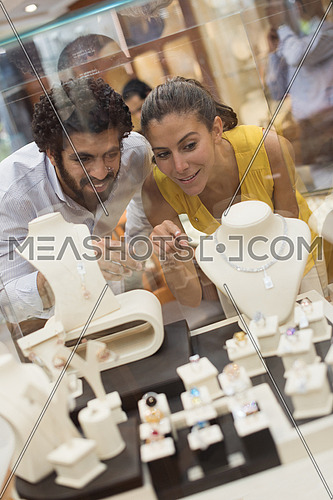 Young middle eastern happy couple enjoying while looking jewelry in the window of a luxury jewelry store