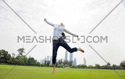 pretty healthy young woman jump and exercise fitness on grass in green park with city in background