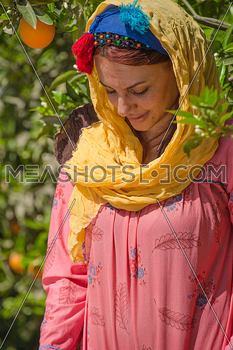 a female egyptian farmer carying oranges in her traditional dress