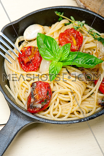 italian spaghetti pasta with baked tomatoes  basil and thyme sauce on a cast iron skillet