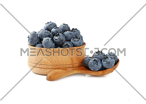 Close up portion of fresh washed blueberry berries with water drops in one rustic natural wooden scoop spoon and bowl isolated on white, low angle side view