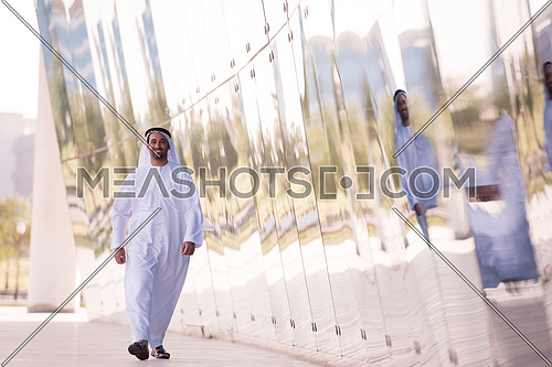 handsome middle eastern business man walking in front of modern office building
