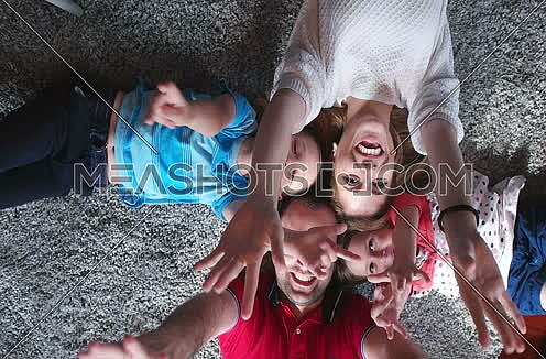 top view of  happy family lying on floor with heads together