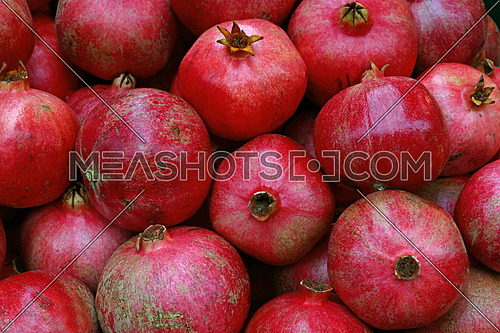 Fresh red ripe pomegranates at retail market stall display, close up, elevated high angle view
