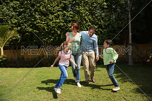 happy middle eastern young family enjoys a sunny day playing in the yard