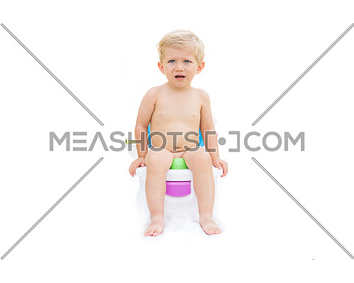 Infant boy, white caucasian serious and sitting on the potty with white background.