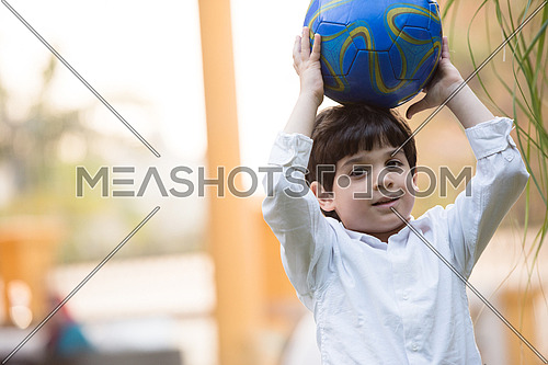 portrait of middle eastern boy with a ball sunny summer day in the yard