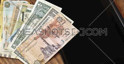1 doller and 1 egyptian pound on wood background and tablet