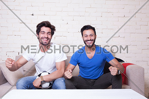 two young men sitting on a couch cheering for egypt