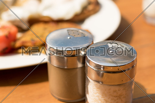 Salt and Pepper shakers on a wooden breakfast table