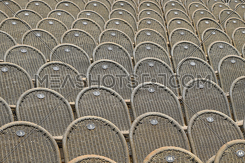 Rows of empty grey brown wicker seats in open air concert hall auditorium, low angle side view