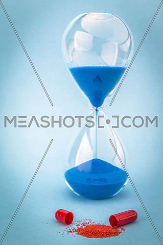 Hourglass marks the time of taking daily medication, isolated on blue background