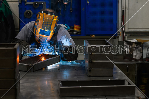 Professional welder performs work with metal parts in factory, sparks and electricity. Industry worker banner. High quality photo