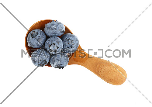 Close up several fresh washed blueberry berries with water drops in one rustic natural wooden scoop spoon isolated on white background, elevated top view, directly above