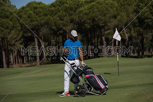 handsome middle eastern golf playerwalking with wheel bag at course on beautiful  sunny day