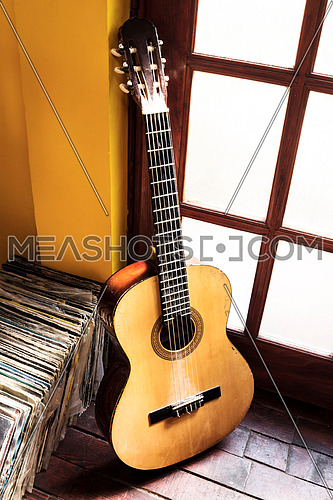 Old dusty guitar and records on the wooden flor