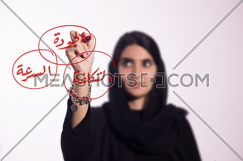 Arabian middle eastern business woman writing with a marker on virtual screen  in arabic cost, quality & speed
isolated on white background