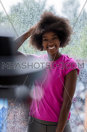 portrait of young afro american woman in gym on work out break while teaking breath and fresh water rainy day and bad weather outdooor