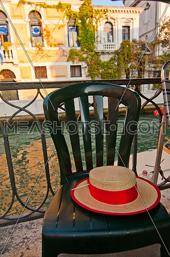 Venice Italy gondolier hat on a chair with canal on background