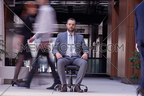 business man sitting in office chair,  people group  passing by: Concept of time, rush, organization