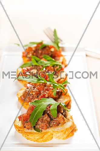 fresh tipycal italian bruschetta with tomato and arugula on top