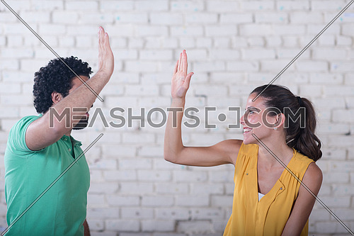 two young middle eastern informal businessman celebrating success with high five to each other in creative office