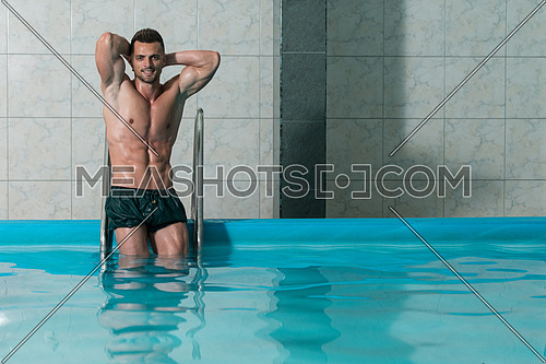 Happy Attractive Man Resting Relaxed On Edge Of Swimming Pool