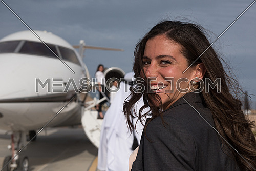 young successful middle eastern business woman walking with Arab business partner in front of private airplane
