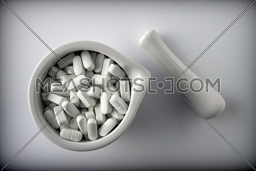 Several pills inside white mortar, conceptual image