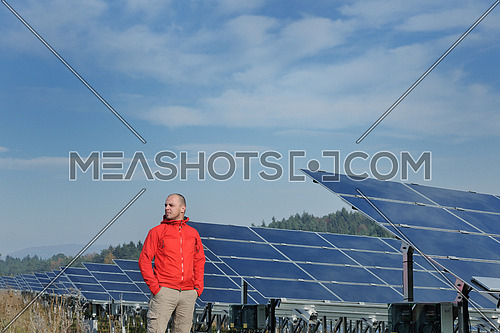 Male engineer at work place, solar panels plant industy in background