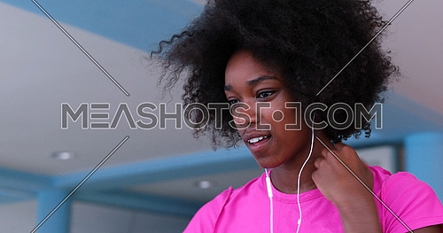 portrait of young afro american woman in gym on workout break while listening music on earphone