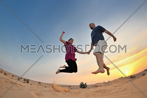 relaxed young pasionate couple enjoying the sunset  beauty on their honeymoon, on a desert with orange background