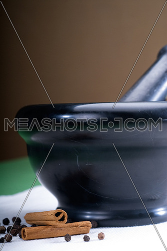 black stone mortar and pestel with cinnamon and pepper